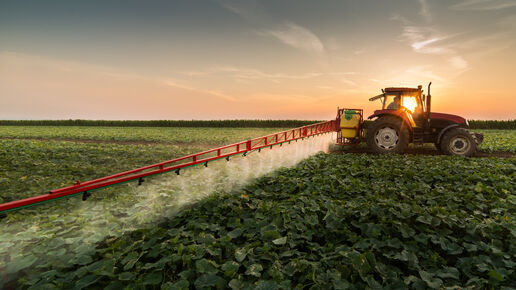 Tractor spraying pesticides on vegetable field with sprayer at spring